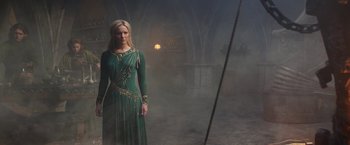 Movie still from “The Lord of the Rings: The Rings of Power” (2022), created by Patrick McKay – A woman in a green dress standing in a dark room; Wide shot, Low angle