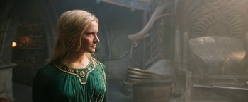 Movie still from “The Lord of the Rings: The Rings of Power” (2022), created by Patrick McKay – A woman in a green dress standing next to a staircase; Close Up shot, Low angle