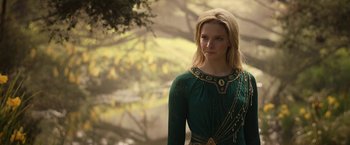 Movie still from “The Lord of the Rings: The Rings of Power” (2022), created by Patrick McKay – A woman in a green dress standing next to a tree; Close Up shot, Over the shoulder angle