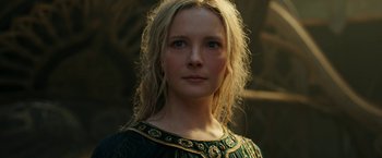 Movie still from “The Lord of the Rings: The Rings of Power” (2022), created by Patrick McKay – A woman with blonde hair wearing a green and gold dress; Close Up shot, Low angle