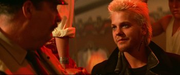 Movie still from “The Lost Boys” (1987), directed by Joel Schumacher – A man and a woman are standing in front of a painting; Close Up shot, Over the shoulder angle