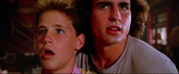 Movie still from “The Lost Boys” (1987), directed by Joel Schumacher – A man and a boy looking at the camera; Close Up shot, Low angle
