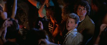 Movie still from “The Lost Boys” (1987), directed by Joel Schumacher – A group of young people sitting in a room; Medium shot, High angle