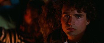 Movie still from “The Lost Boys” (1987), directed by Joel Schumacher – A person with curly red hair; Close Up shot, Low angle