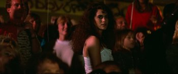 Movie still from “The Lost Boys” (1987), directed by Joel Schumacher – A woman with long hair is standing in front of a group of people; Medium shot, Low angle