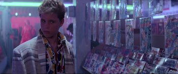 Movie still from “The Lost Boys” (1987), directed by Joel Schumacher – A woman standing in front of a display of comic books; Medium shot, Over the shoulder angle