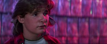 Movie still from “The Lost Boys” (1987), directed by Joel Schumacher – A young man in a white t - shirt and a red scarf; Close Up shot, Low angle