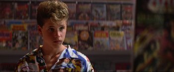 Movie still from “The Lost Boys” (1987), directed by Joel Schumacher – A young boy in front of a bunch of movie posters; Close Up shot, Over the shoulder angle