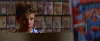 Movie still from “The Lost Boys” (1987), directed by Joel Schumacher – A young boy in front of a wall of comic books; Close Up shot, Over the shoulder angle