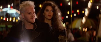 Movie still from “The Lost Boys” (1987), directed by Joel Schumacher – A man and a woman standing next to each other on a street; Close Up shot, Low angle