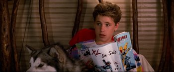 Movie still from “The Lost Boys” (1987), directed by Joel Schumacher – A young boy sitting in front of a cat reading a comic book; Medium shot, High angle