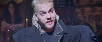Movie still from “The Lost Boys” (1987), directed by Joel Schumacher – A man with blonde hair and blue eyes looking at the camera; Close Up shot, Over the shoulder angle