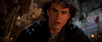 Movie still from “The Lost Boys” (1987), directed by Joel Schumacher – A man with curly hair and a black jacket; Close Up shot, Over the shoulder angle