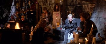 Movie still from “The Lost Boys” (1987), directed by Joel Schumacher – A group of people sitting in a room with lit candles; Wide shot, High angle