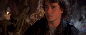 Movie still from “The Lost Boys” (1987), directed by Joel Schumacher – A young man in a brown jacket looking at the camera; Close Up shot, Over the shoulder angle