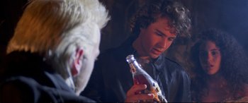 Movie still from “The Lost Boys” (1987), directed by Joel Schumacher – A young man holding a bottle of soda and looking at another young man; Close Up shot, Over the shoulder angle