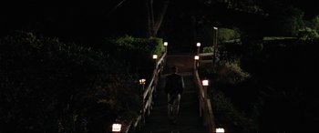 Movie still from “The Lost Boys” (1987), directed by Joel Schumacher – A man walking down a set of stairs at night; Extreme Wide shot, High angle
