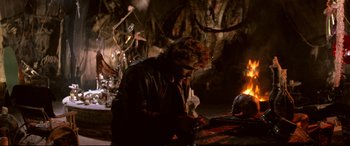 Movie still from “The Lost Boys” (1987), directed by Joel Schumacher – A man sitting in front of an open fire; Medium shot, Over the shoulder angle