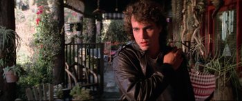 Movie still from “The Lost Boys” (1987), directed by Joel Schumacher – A man in a leather jacket is posing for a picture; Close Up shot, Low angle