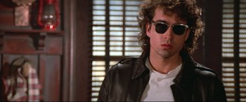 Movie still from “The Lost Boys” (1987), directed by Joel Schumacher – A person wearing sunglasses and a leather jacket; Close Up shot, Low angle