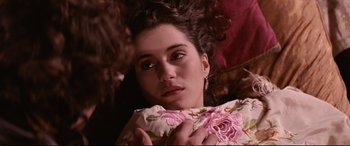 Movie still from “The Lost Boys” (1987), directed by Joel Schumacher – A woman laying on the ground holding a pillow; Close Up shot, Overhead angle