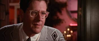 Movie still from “The Lost Boys” (1987), directed by Joel Schumacher – A person wearing glasses and a sweater; Close Up shot, Over the shoulder angle