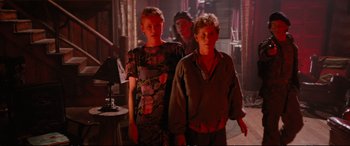 Movie still from “The Lost Boys” (1987), directed by Joel Schumacher – A group of people standing next to each other in a room; Medium shot, Over the shoulder angle