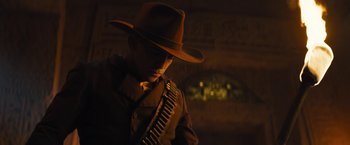 Movie still from “The Lost City” (2022), directed by Aaron Nee – A man wearing a hat and holding a rifle; Medium shot, Low angle