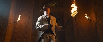 Movie still from “The Lost City” (2022), directed by Aaron Nee – An older man holding a fire torch in a dark room; Medium shot, Low angle