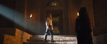 Movie still from “The Lost City” (2022), directed by Aaron Nee – A man is walking down some stairs in a building; Wide shot, Low angle