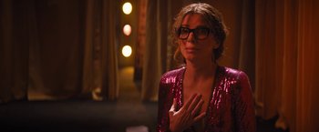 Movie still from “The Lost City” (2022), directed by Aaron Nee – A woman wearing glasses and a red dress; Medium shot, Over the shoulder angle