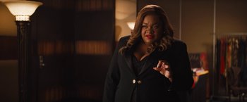 Movie still from “The Lost City” (2022), directed by Aaron Nee – A woman in a black suit and red lipstick; Medium shot, Over the shoulder angle