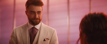 Movie still from “The Lost City” (2022), directed by Aaron Nee – A man with a beard and a suit and tie; Close Up shot, Over the shoulder angle