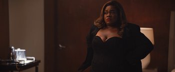 Movie still from “The Lost City” (2022), directed by Aaron Nee – A woman in a black dress is standing in a dark room; Medium shot, Over the shoulder angle