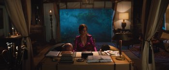 Movie still from “The Lost City” (2022), directed by Aaron Nee – A woman sitting at a table in front of an aquarium; Medium shot, High angle