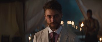 Movie still from “The Lost City” (2022), directed by Aaron Nee – A person wearing a suit and tie; Close Up shot, Over the shoulder angle