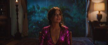 Movie still from “The Lost City” (2022), directed by Aaron Nee – A woman in a pink dress is sitting in a chair; Medium shot, Over the shoulder angle