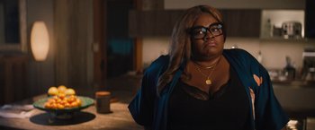 Movie still from “The Lost City” (2022), directed by Aaron Nee – A woman wearing glasses is standing in a room; Medium shot, Over the shoulder angle