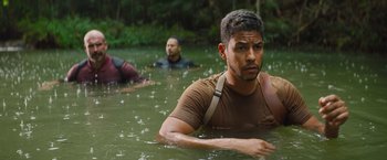 Movie still from “The Lost City” (2022), directed by Aaron Nee – A man in a brown shirt in a body of water; Medium shot, High angle