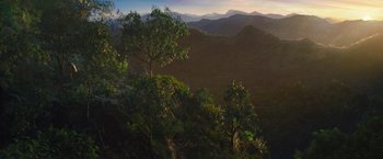 Movie still from “The Lost City” (2022), directed by Aaron Nee – A view of a mountain range with trees in the foreground; Extreme Wide shot, High angle