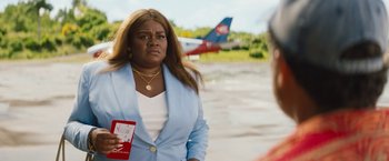 Movie still from “The Lost City” (2022), directed by Aaron Nee – A woman in a blue jacket holding a red book; Medium shot, Over the shoulder angle