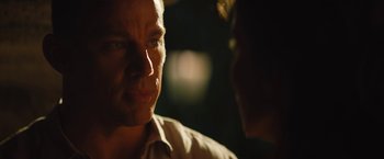 Movie still from “The Lost City” (2022), directed by Aaron Nee – A man is looking at another man in the dark; Close Up shot, Over the shoulder angle