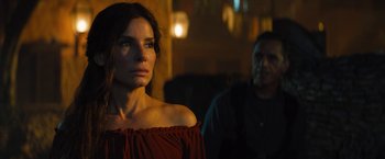 Movie still from “The Lost City” (2022), directed by Aaron Nee – A woman standing next to a man in a dark room; Close Up shot, Over the shoulder angle