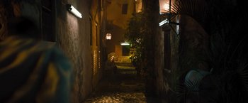 Movie still from “The Lost City” (2022), directed by Aaron Nee – An alleyway at night with a person sitting on a bench; Extreme Wide shot, High angle