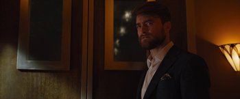 Movie still from “The Lost City” (2022), directed by Aaron Nee – A man in a suit and tie standing in front of a mirror; Close Up shot, Over the shoulder angle