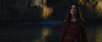Movie still from “The Lost City” (2022), directed by Aaron Nee – A woman standing in front of a body of water; Medium shot, Over the shoulder angle