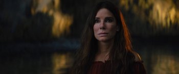Movie still from “The Lost City” (2022), directed by Aaron Nee – A beautiful woman with long brown hair looking at the camera; Close Up shot, Over the shoulder angle
