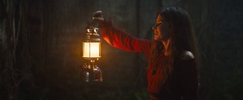 Movie still from “The Lost City” (2022), directed by Aaron Nee – A woman is holding a lantern in the dark; Medium shot, Low angle