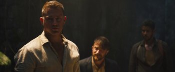 Movie still from “The Lost City” (2022), directed by Aaron Nee – Two men standing next to each other in the dark; Medium shot, Over the shoulder angle