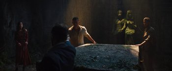 Movie still from “The Lost City” (2022), directed by Aaron Nee – A man standing in front of a statue taking a picture; Wide shot, Over the shoulder angle
